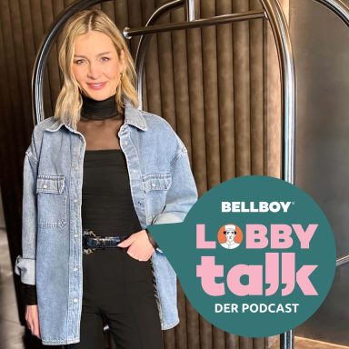 Frau in Jeansjacke und schwarzem Outfit steht vor einem modernen Raumteil.