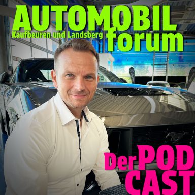Ein Mann sitzt vor einem Auto im AUTOMOBILforum mit dem Titel „Der PODCAST“.